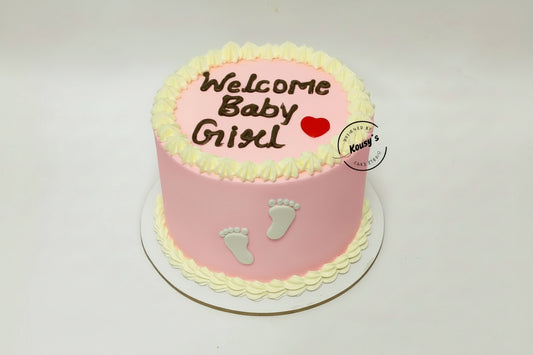 Pink baby shower cake with 'Welcome Baby Girl' text and footprints on a white background